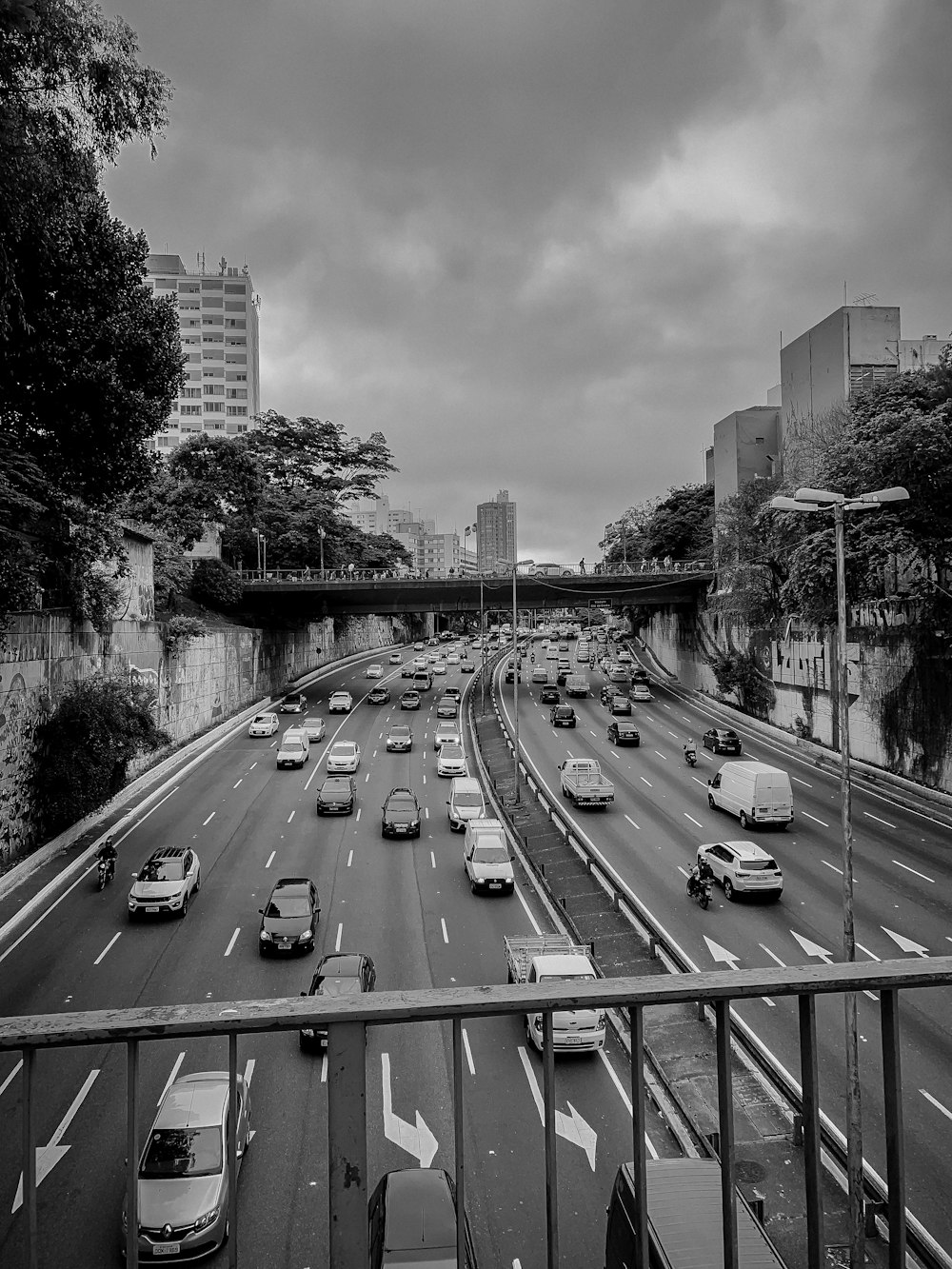 grayscale photography of different vehicles on road viewing city with high-rise buildings