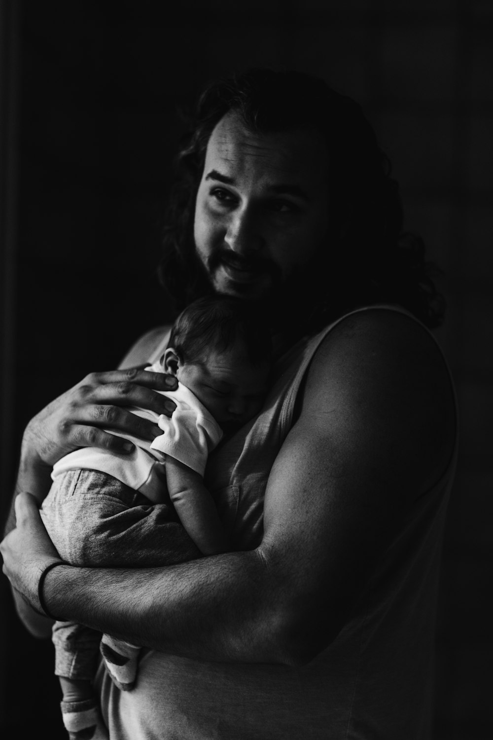 grayscale photography of man carrying a baby