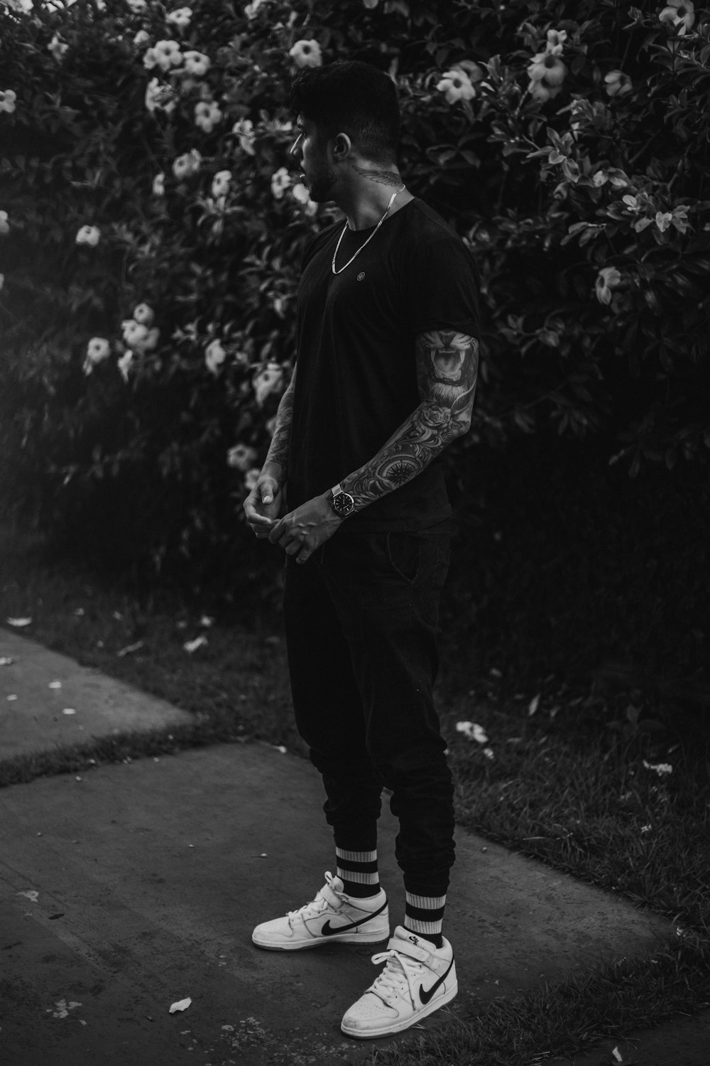 man with tattoo on his arms standing near bushes