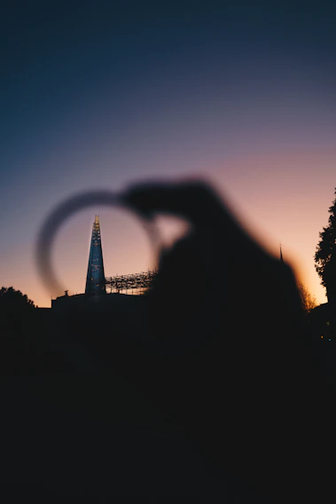 A panoramic view of London's iconic skyline at dusk, with the Shard and the Gherkin glowing against a deep blue sky.
