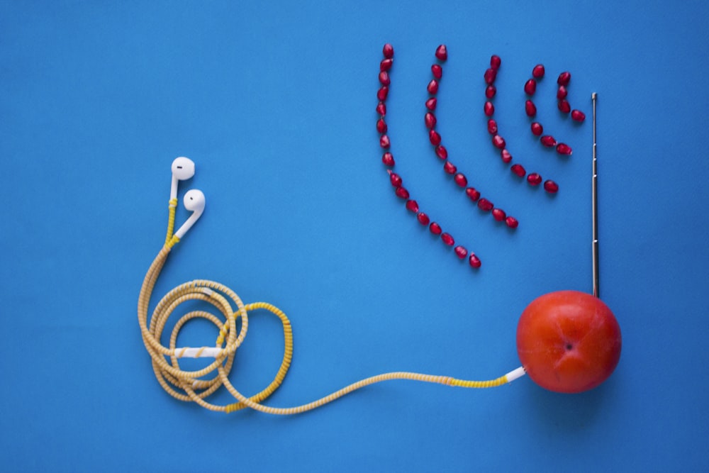white earbuds connected to orange tomato with antenna