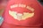 A red baseball cap features gold embroidered wings and the text 'Wings Over Miami.' The stitching includes a stylized emblem resembling a shield flanked by wings.