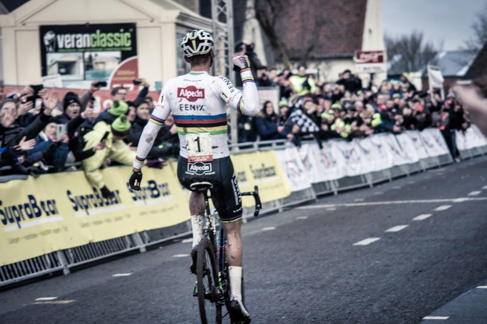 a man riding a bike down a street next to a crowd