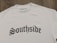 A white T-shirt displayed on a wooden surface with the word 'Southside' printed in bold, gothic-style black lettering. A clothing label reading 'VannyClothingCo.' is visible near the collar, and a blank tag is attached to the shirt.