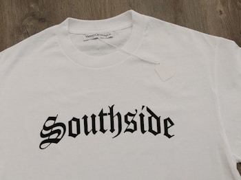 A white T-shirt displayed on a wooden surface with the word 'Southside' printed in bold, gothic-style black lettering. A clothing label reading 'VannyClothingCo.' is visible near the collar, and a blank tag is attached to the shirt.