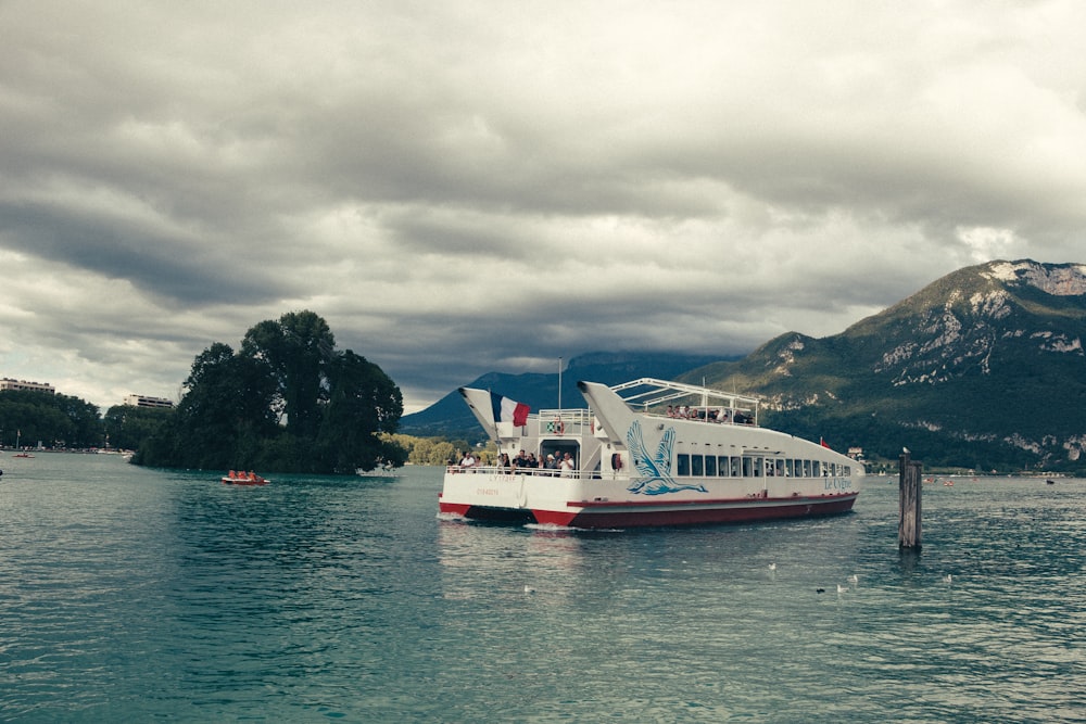 white and red passenger boat floating on body of water near island