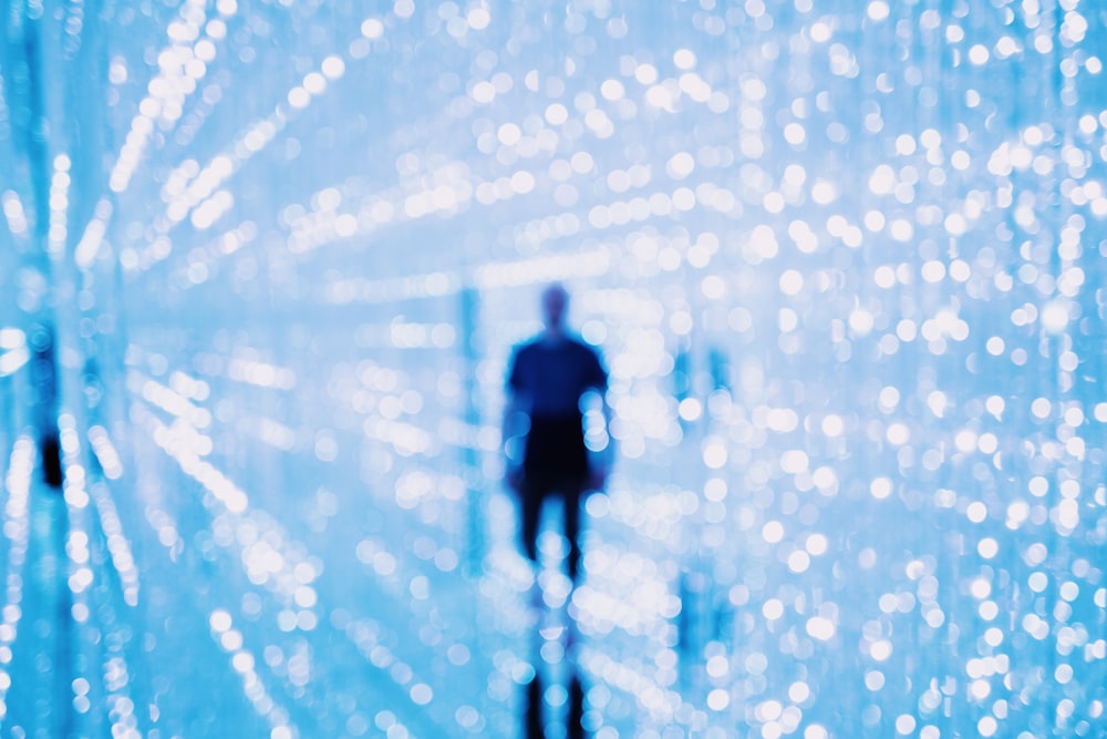 man stands behind bokeh lights