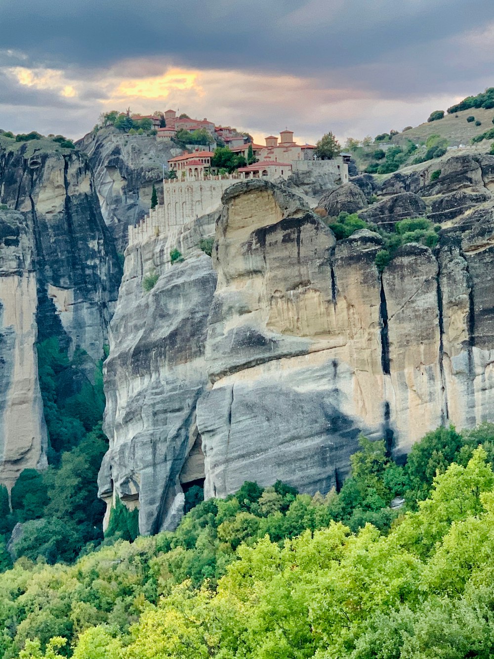 houses on rock cliff under cloudy sky