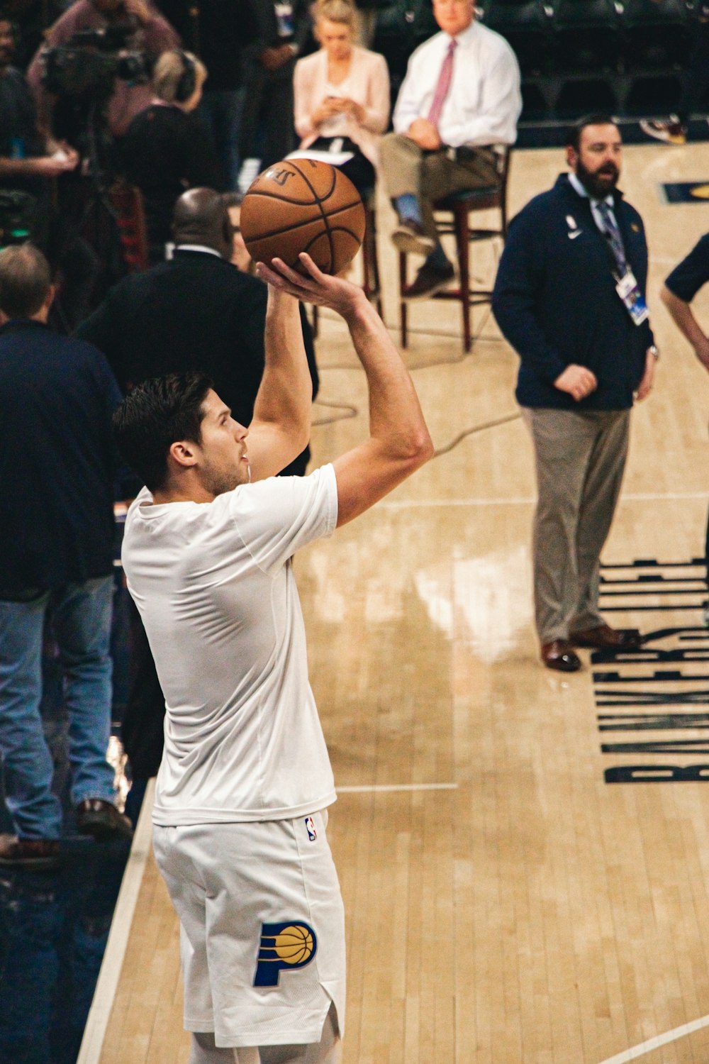 man in white t-shirt and shorts shooting basketball