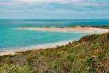 A panoramic view of a pristine sandy beach meeting calm turquoise waters.