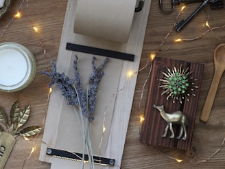 A flat lay of self-care essentials: a candle, a journal, a cup of herbal tea, and a sprig of eucalyptus on a wooden table.