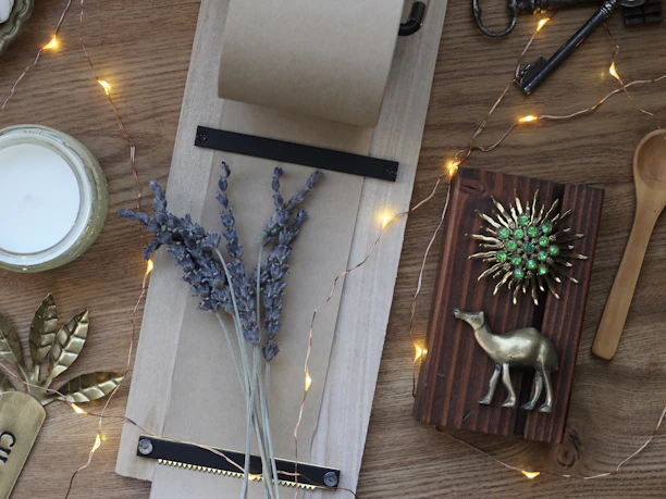 Warm, earthy-toned flat lay featuring lavender and sandal candles surrounded by dried flowers.