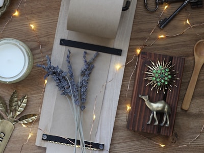 A flat lay of stylish vases, cushions, and candles arranged on a wooden table.