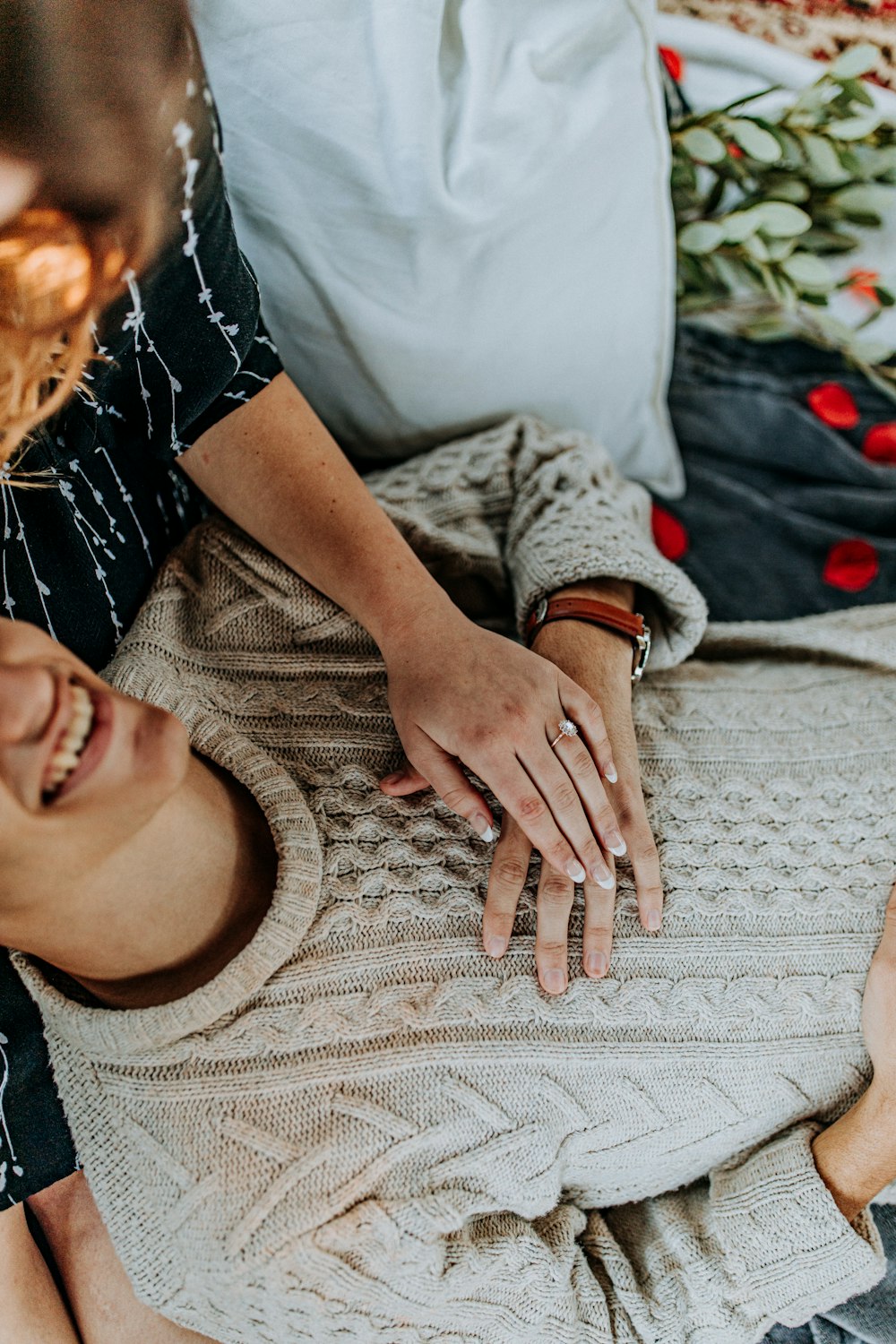 man and woman holding hands while lying on bed