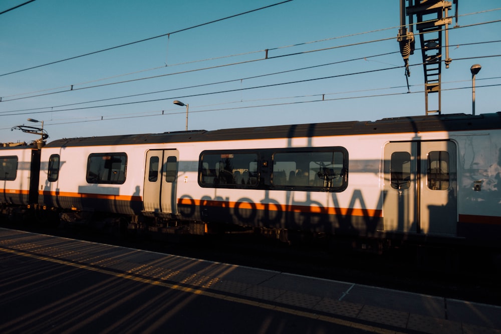 trem branco e cinza ao lado de postes de metal