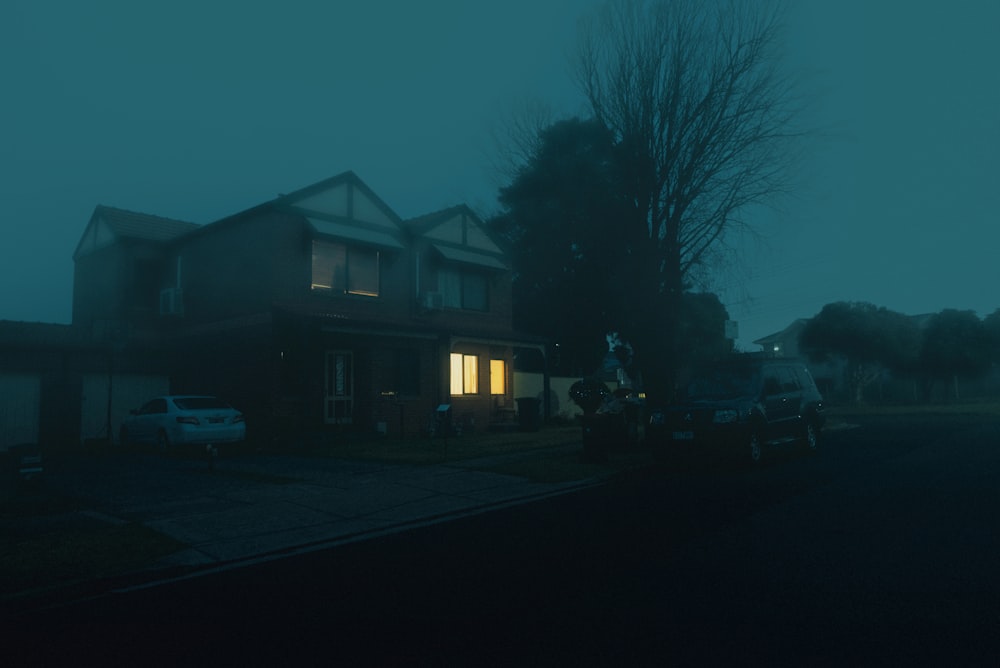 turned-on lights inside two-storey house with two vehicles