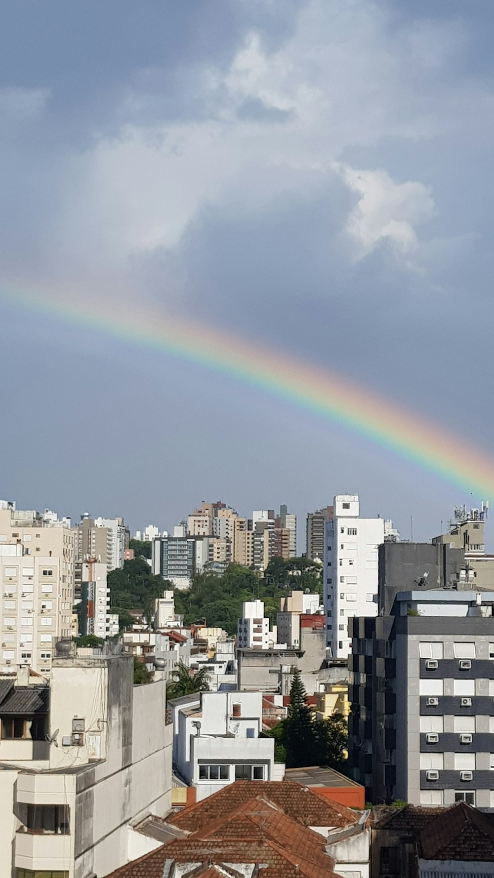 high-angle photography of city buildings under rainbow during daytime