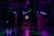Silhouettes of people dancing in a dimly lit room with colorful, neon lighting. A neon sign displays '50's Dance' in the background, and there are balloons in various shades of pink and white on one side. The scene captures a lively and retro-themed dance event.
