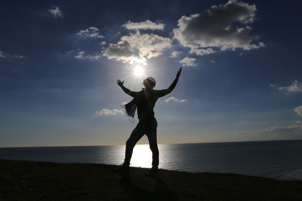 silhouette of standing man on seashore during daytime