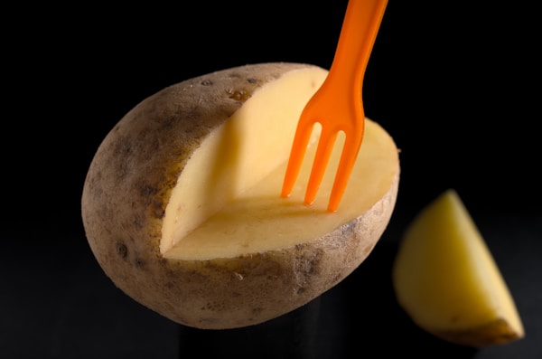 Orange plastic fork on brown potato