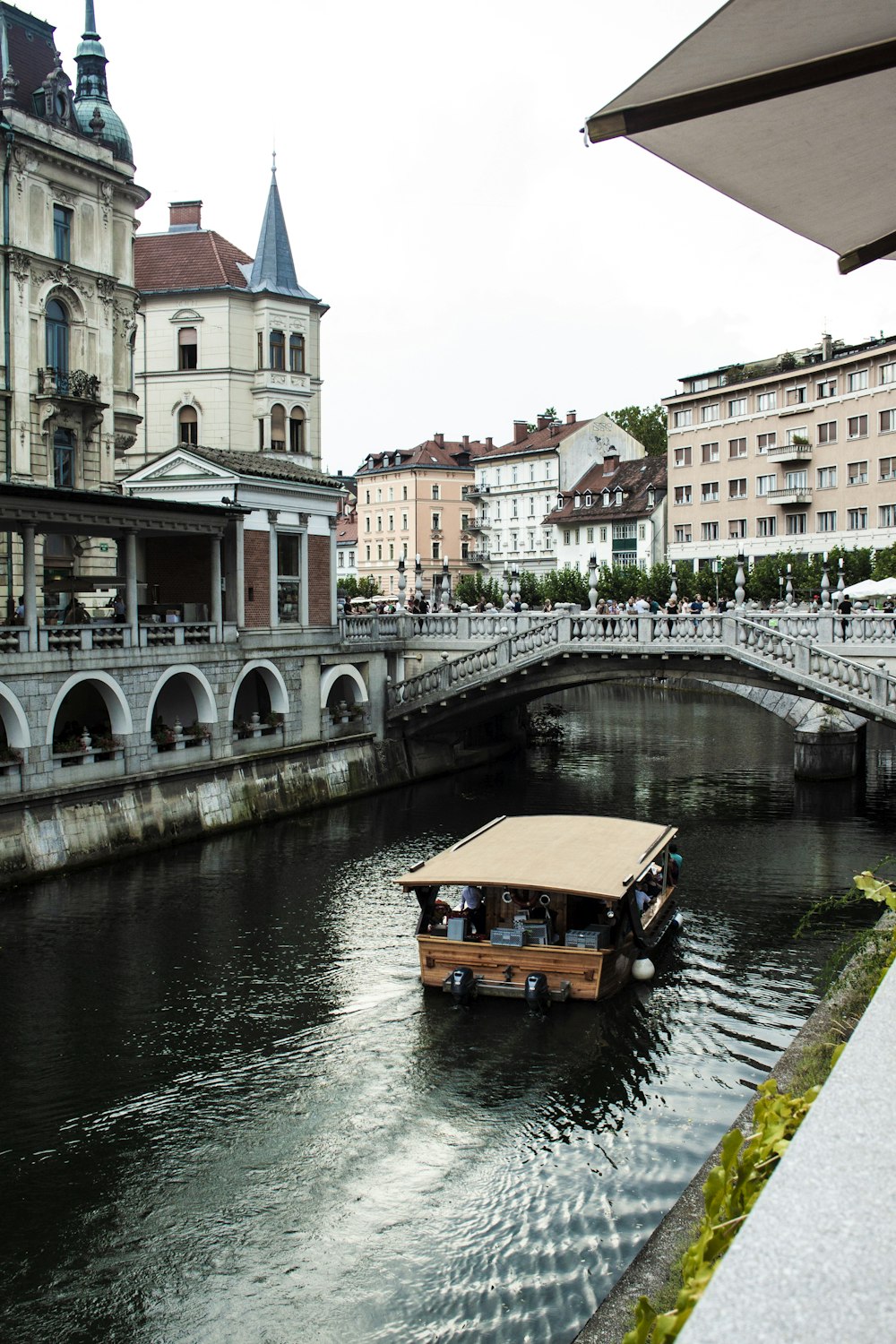 brown touring boat approaching bridge