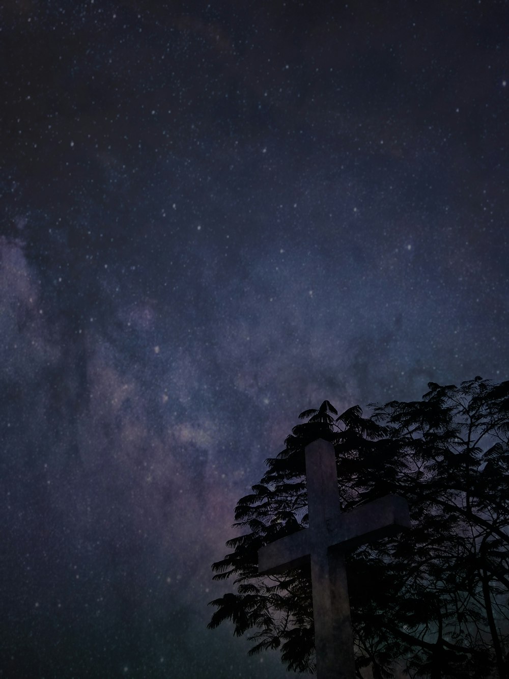 silhouette of cross near trees under galaxy