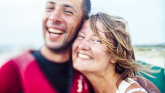 A close-up image of two people smiling widely, suggesting a joyful and happy moment shared between them. The background is blurred, drawing attention to their expressions.