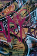 Graffiti artist painting a vibrant mural with red, green, and purple spray paint, embodying the rebellious spirit of not lazy boy.