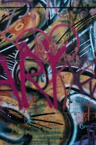 A vibrant neon pink and black graffiti-style explosion with scattered scrap metal and tape.