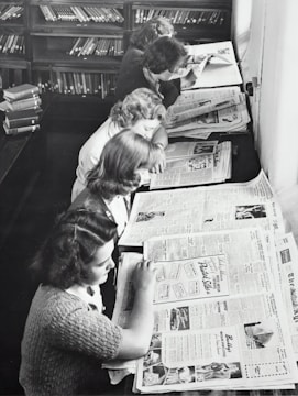 grayscale photo of women reading newspaper