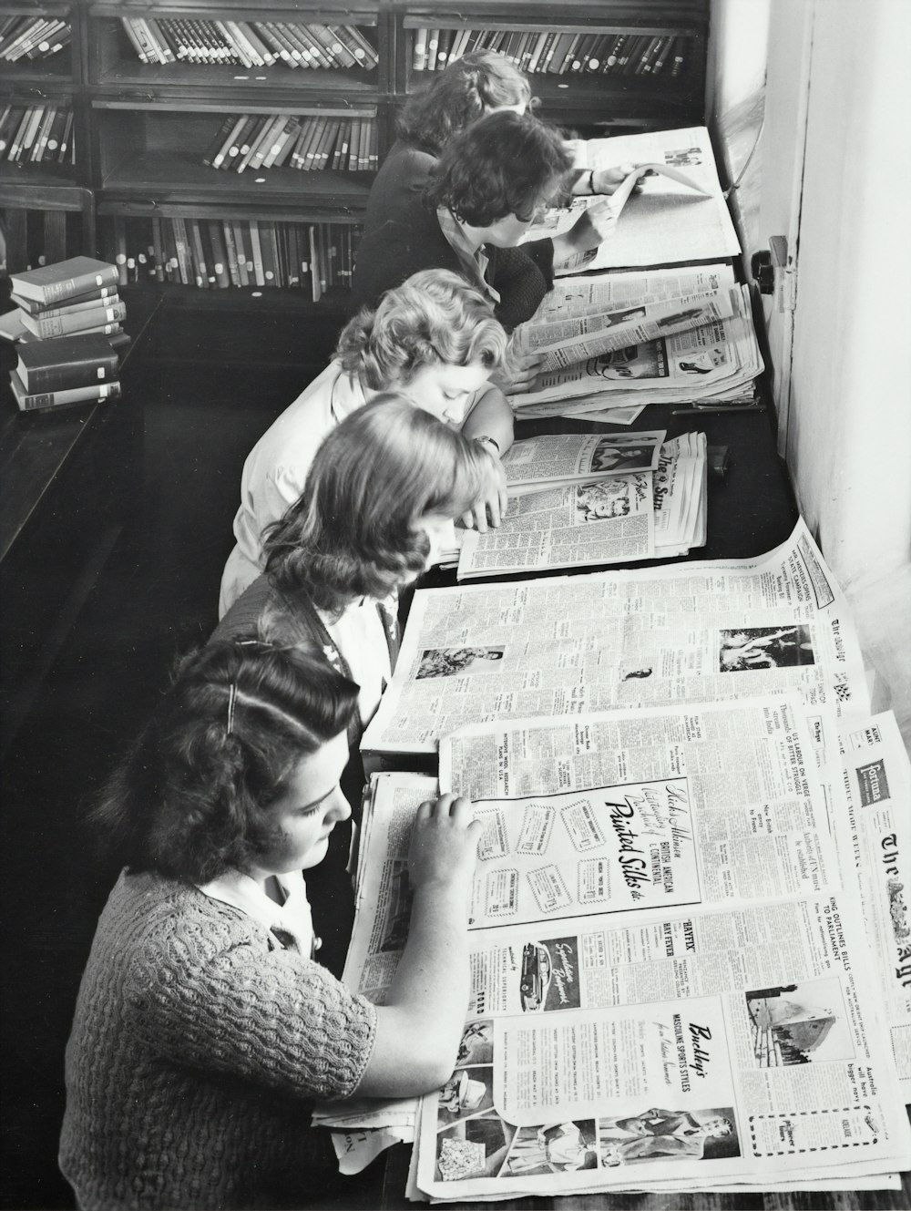 grayscale photo of women reading newspaper