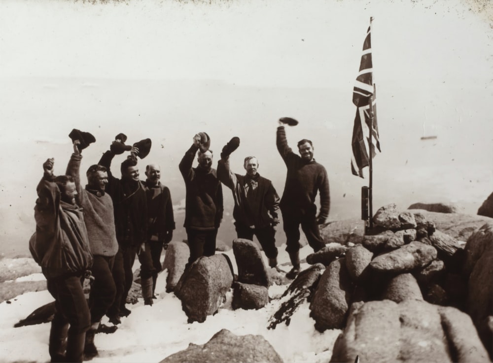 grayscale photo of men standing beside flag