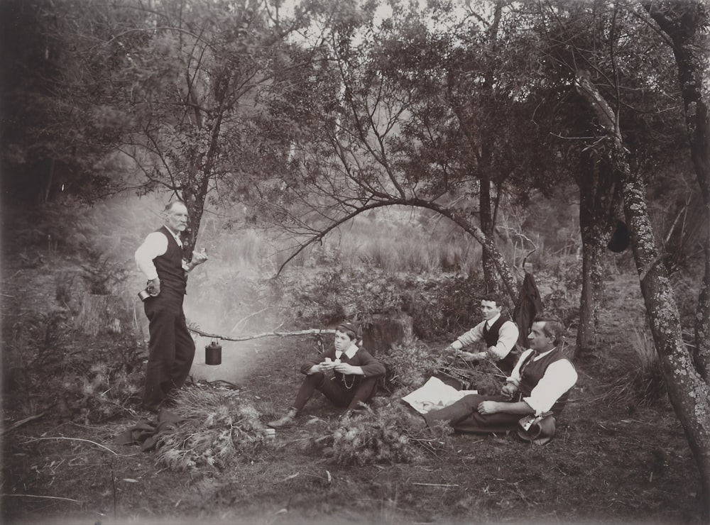 four men sitting on ground near trees