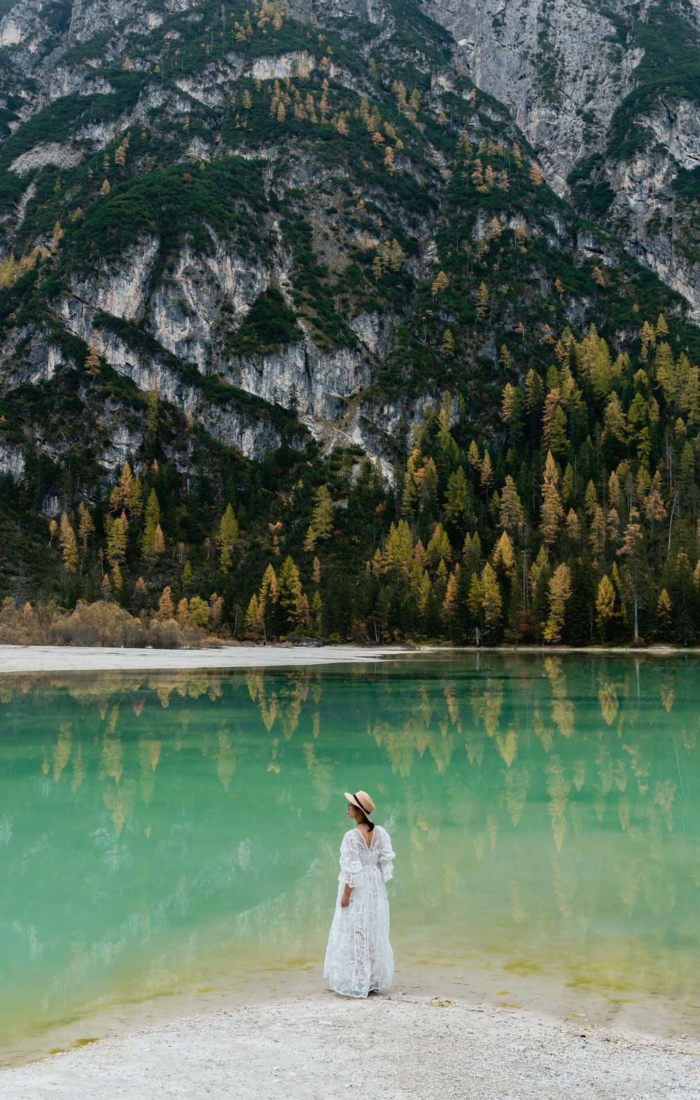 woman in white dress standing beside lake