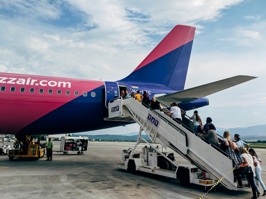 people walking towards airplane, Boarding – People go via stairs on board of an Airbus A320 of the airline Wizzair