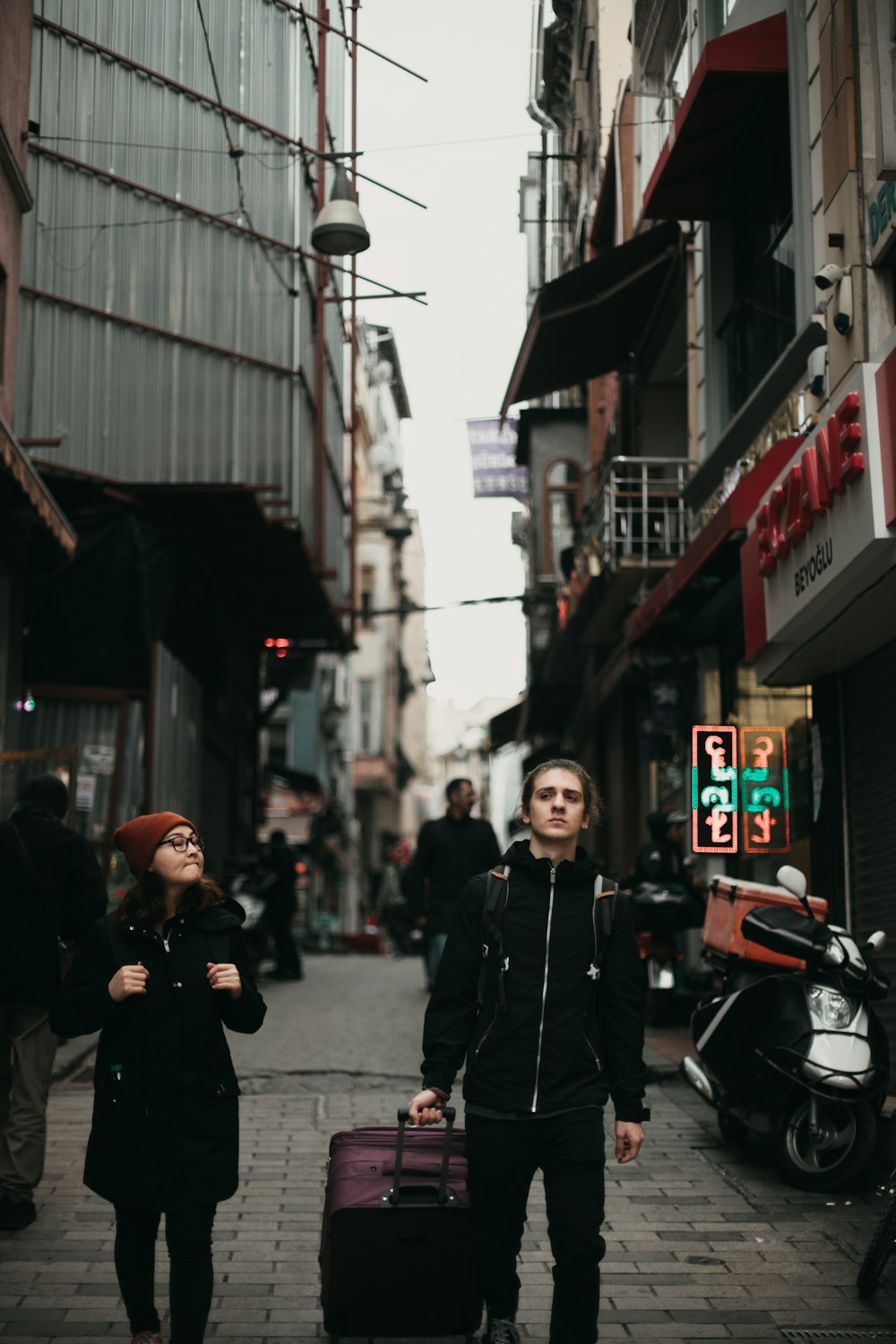 man in black jacket walking on street with luggage