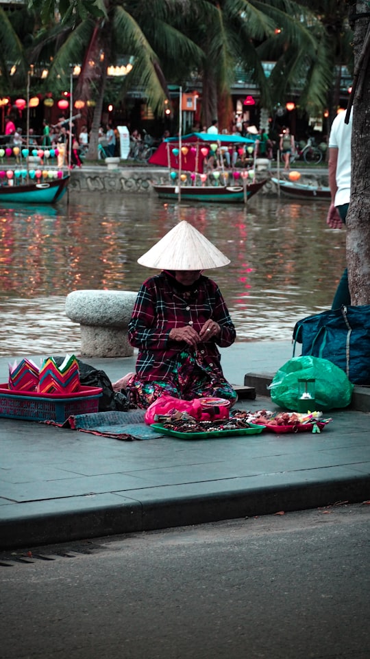 kneeling woman on placemat beside body of water in Hoi An Vietnam