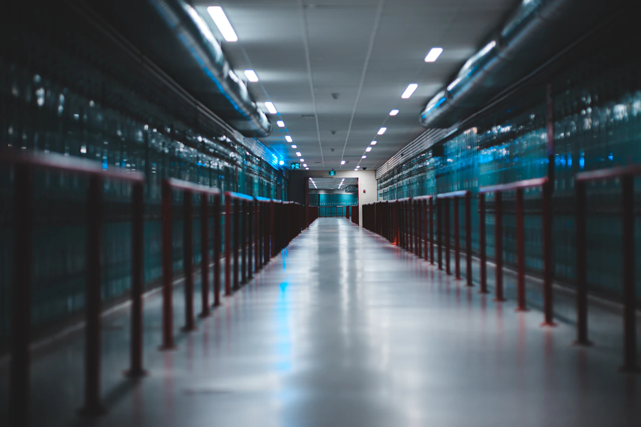 A brightly lit aisle between rows of server cabinets in a data centre
