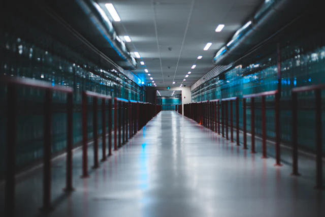 A brightly lit aisle between rows of server cabinets in a data centre