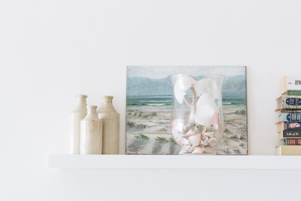 three gray ceramic jars beside painting