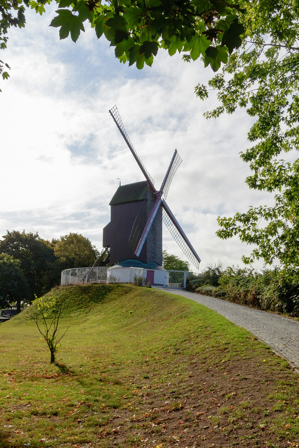 windmill building beside road and near trees during day