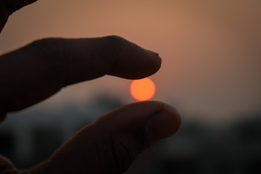 sun between person's fingers