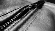 Close-up of a zipper and stitching detail on a luxurious lamb leather jacket.