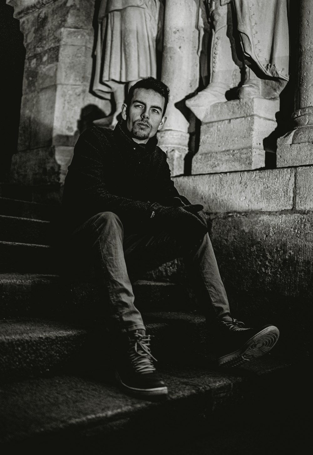grayscale photo of man sitting on staircase