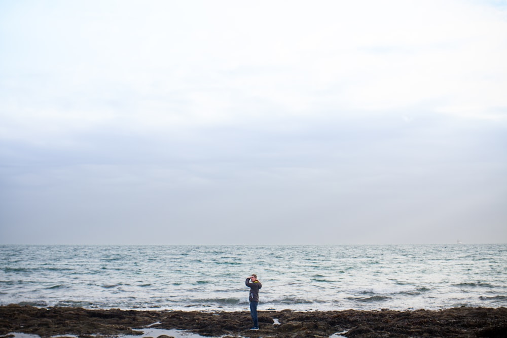 흰 하늘 아래 해안에 서 있는 남자