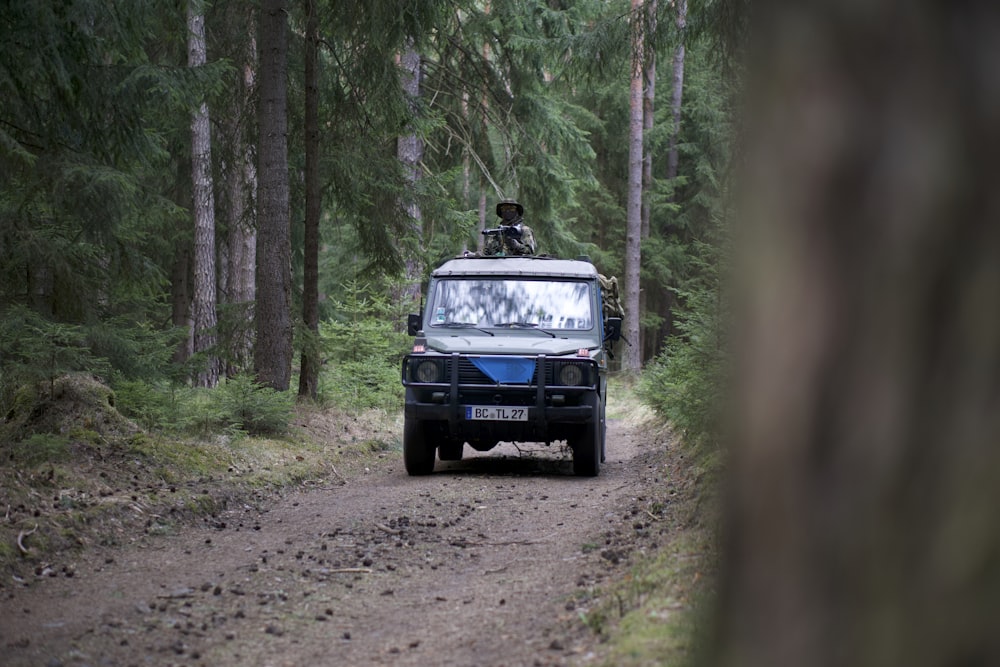 black car on dirt road near trees during day