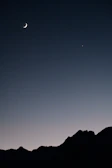 A serene night sky with planets aligned over a silhouette of mountains.