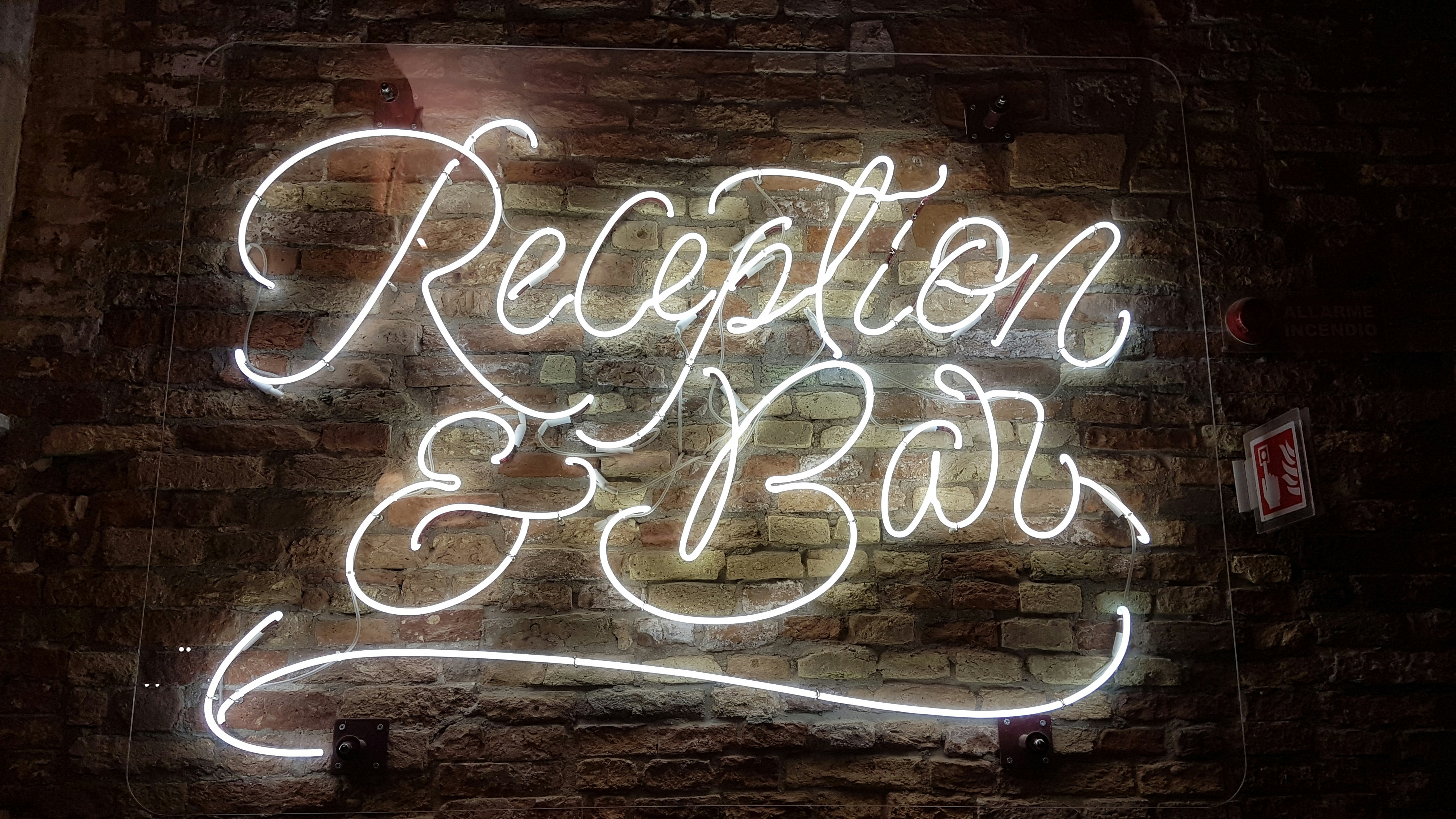 White neon 'Reception & Bar' sign on a brick wall