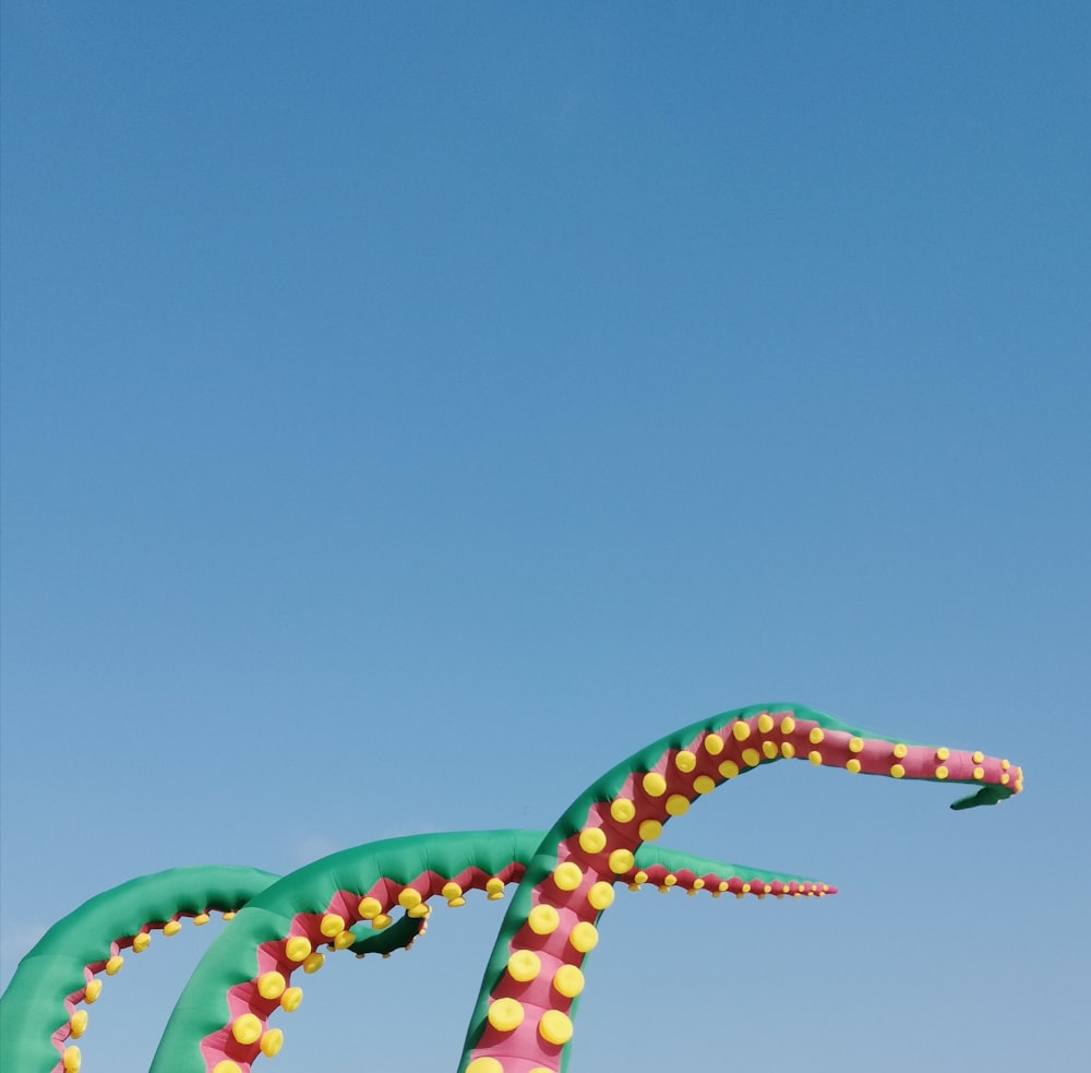 Rote, gelbe und grüne Oktopus-Tentakel-Hüpfburgen unter blauem Himmel