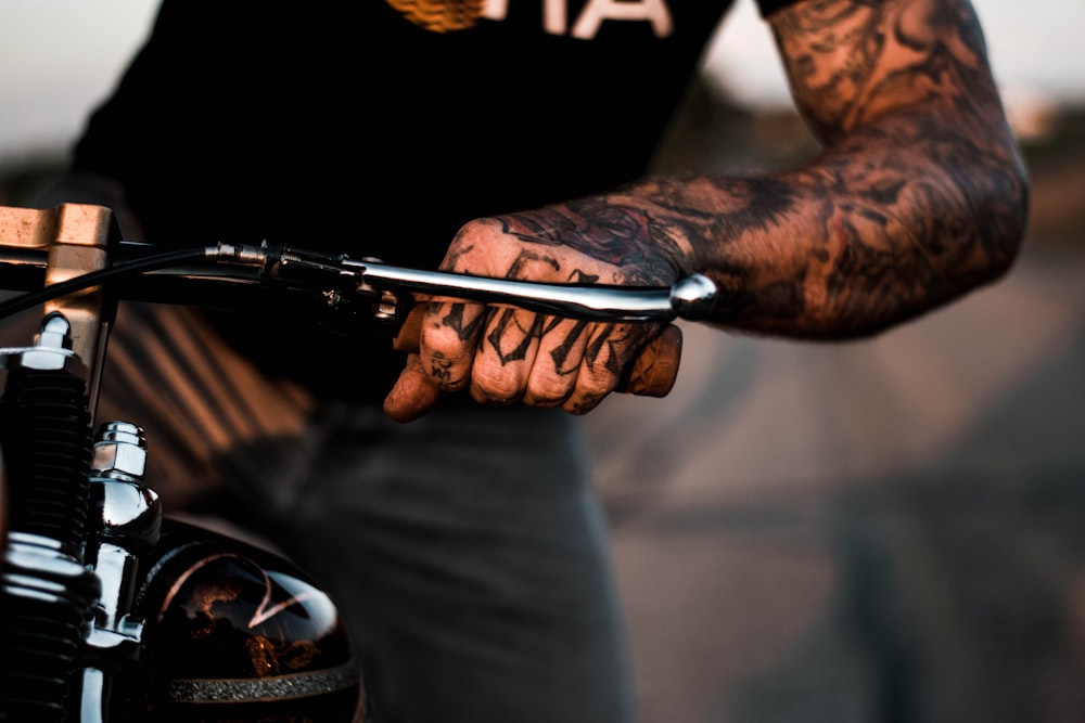 person with tattoos on arm riding motorcycle
